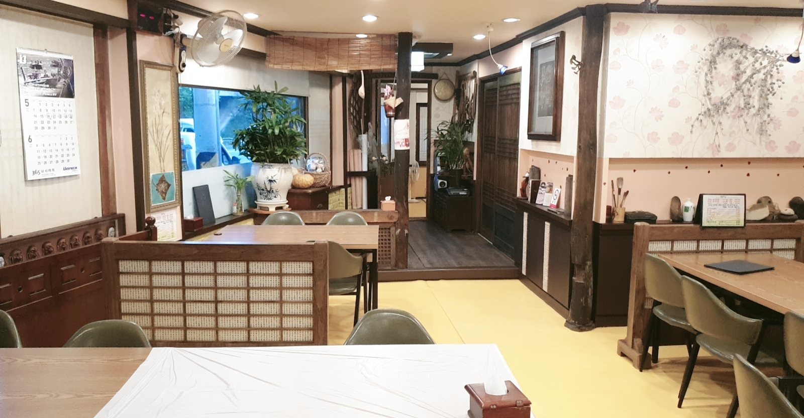 창살 칸막이와 의자·테이블이 놓인 홀, 노란 바닥
